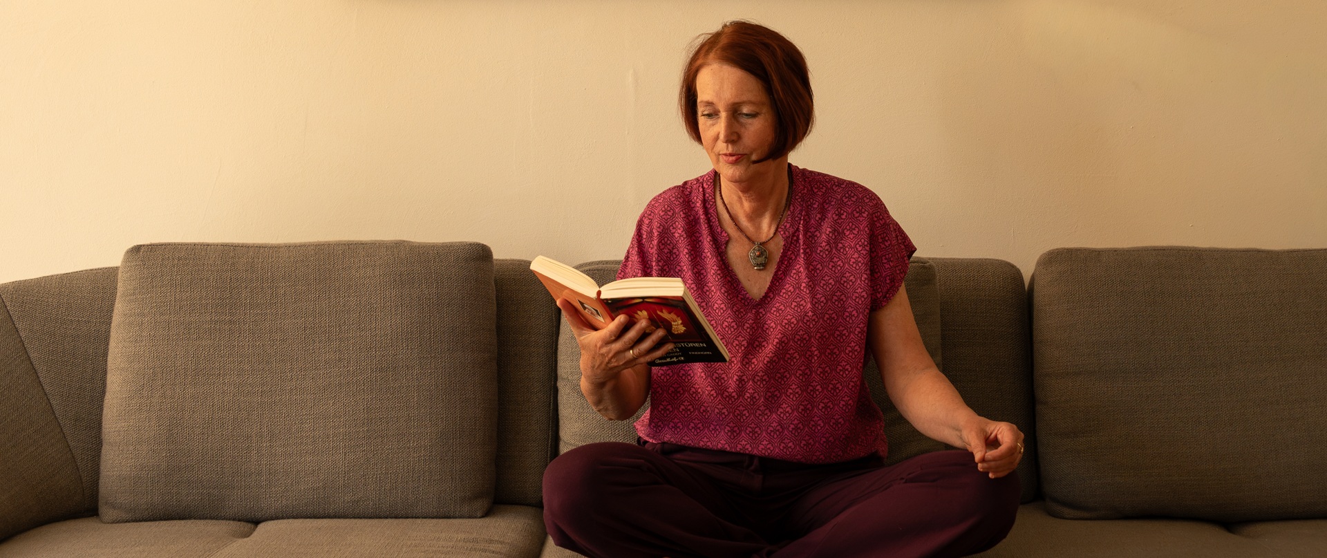 Mareike sitzt auf einem Sofa und liest ein Buch