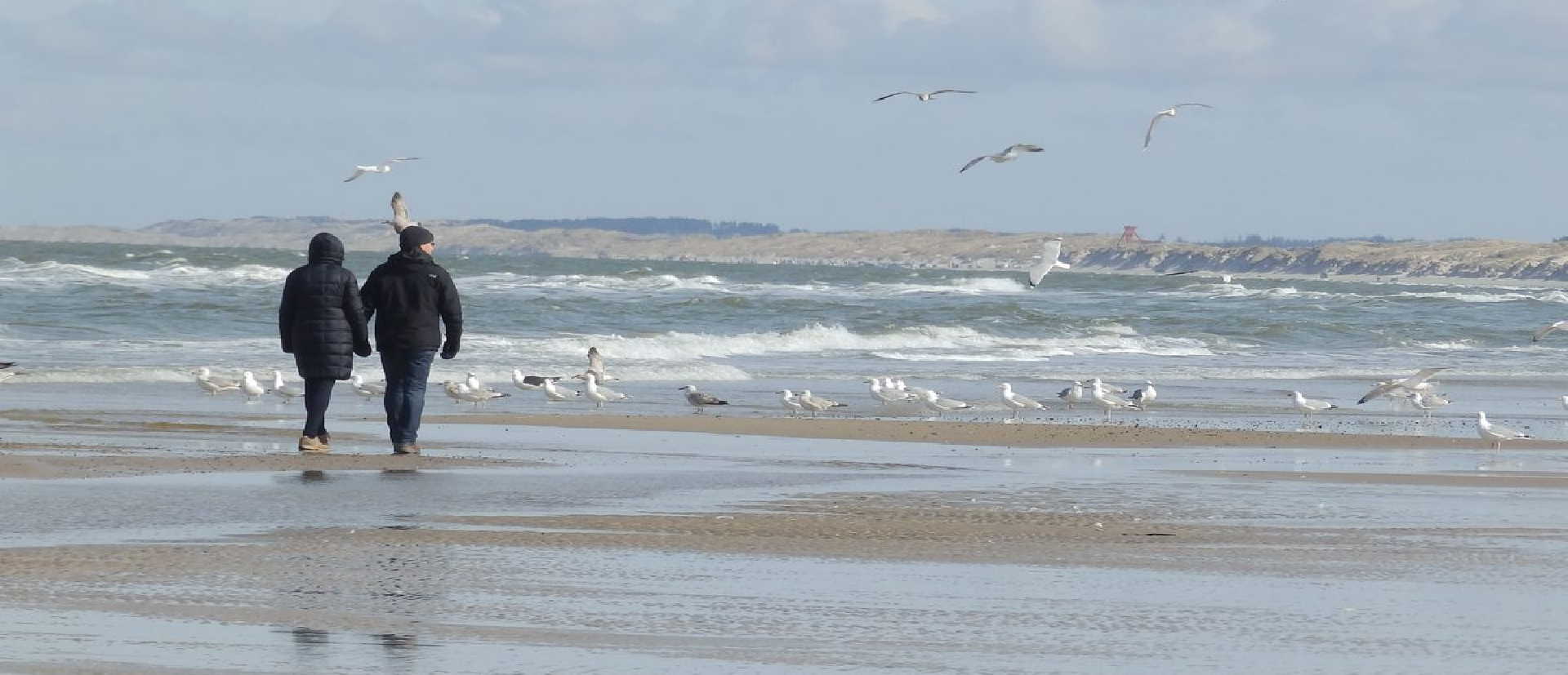 Zwei Personen gehen an einem Strand entlang spazieren